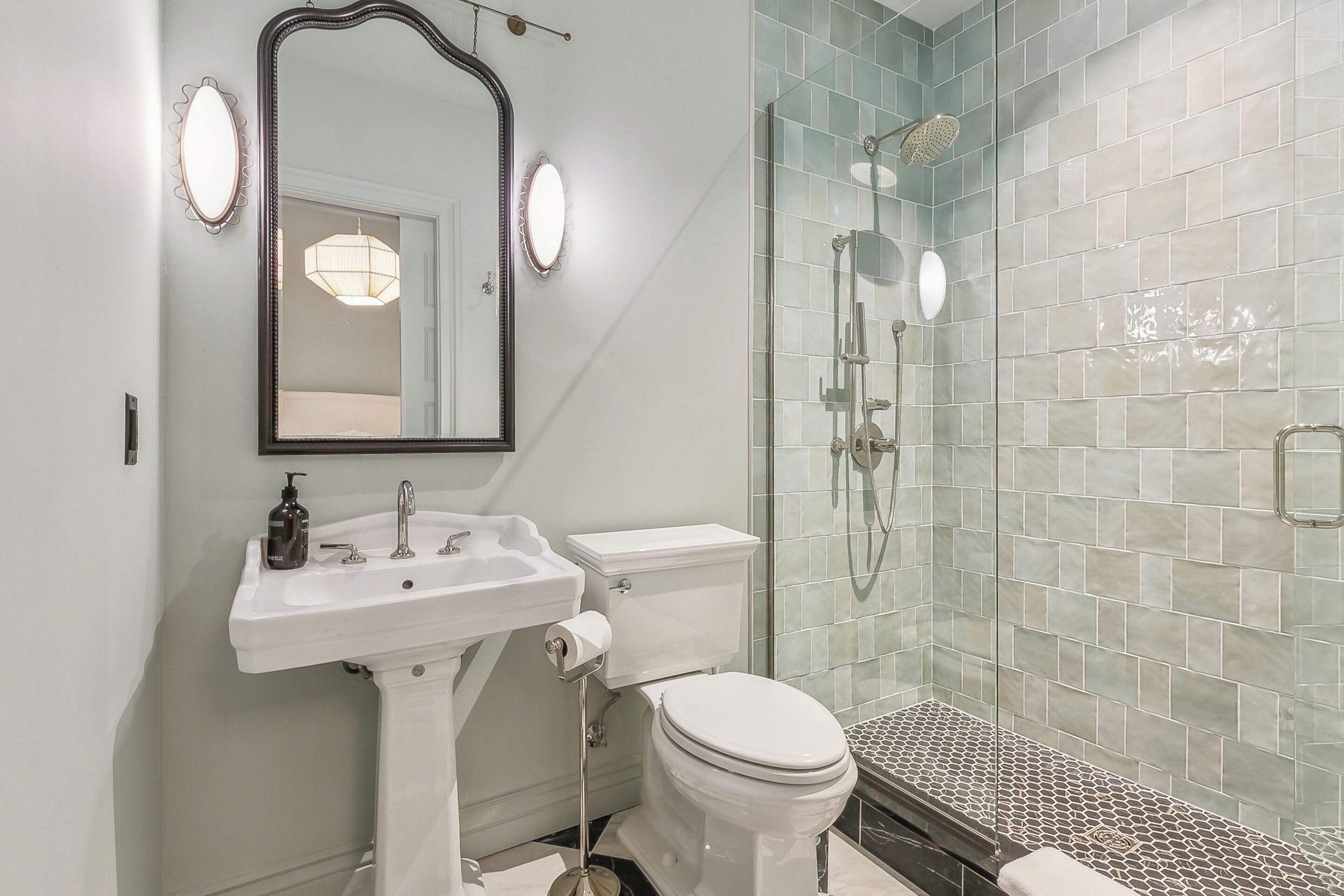 A bathroom with a white sink, a toilet, a mirror, and a glass shower enclosure.