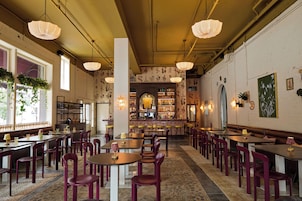 Un interior de restaurante con varias mesas y sillas, una zona de bar y elementos decorativos en las paredes.