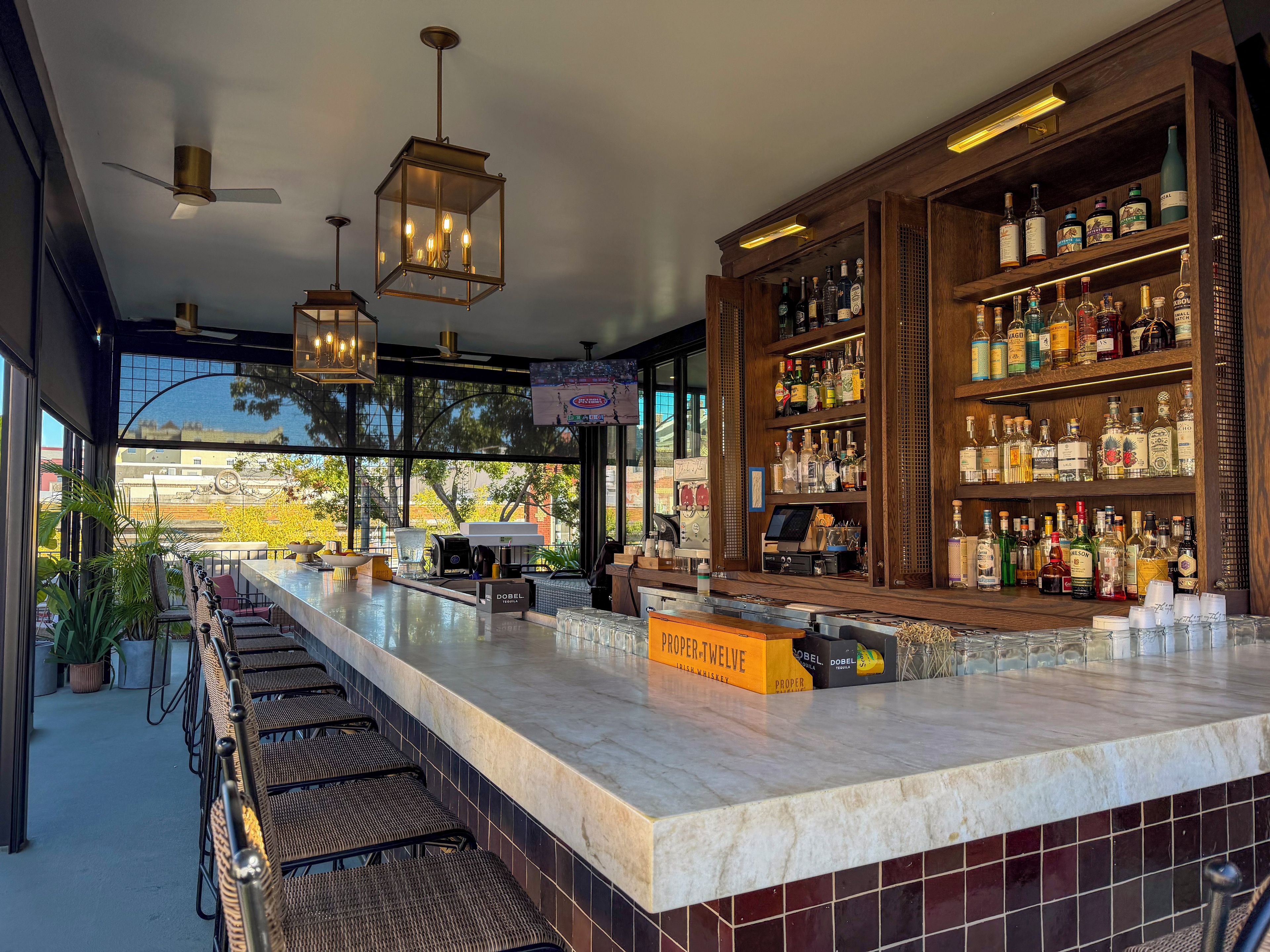 A bar area with a marble countertop, wicker chairs, and a variety of liquor bottles.