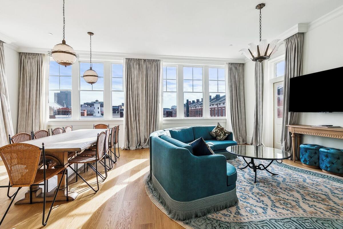 A modern living room with a dining area, large windows, and a city view.