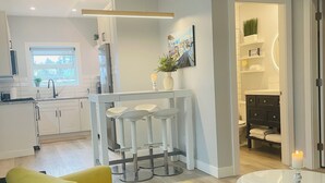 Cocina moderna con armarios blancos, una ventana y una zona de bar con taburetes.