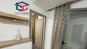 A hallway with a wooden shelf, a decorative bottle, and a door with patterned curtains. - S+2 apartment for rent 15 minutes from the beach on foot  (Mrezga)
