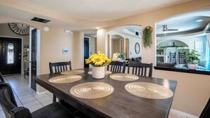 A dining area with a dark wooden table, four chairs, and a vase of yellow flowers. - Air Hockey, Pool, Fireplace, Basketball, & more! (El Paso)