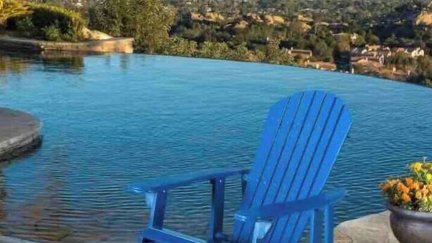 A blue Adirondack chair by a pool with a view of a hilly landscape. - Air Hockey, Pool, Fireplace, Basketball, & more! (El Paso)