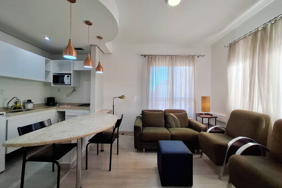 Un espai modern d'estar amb cuina, zona de menjador i seients.