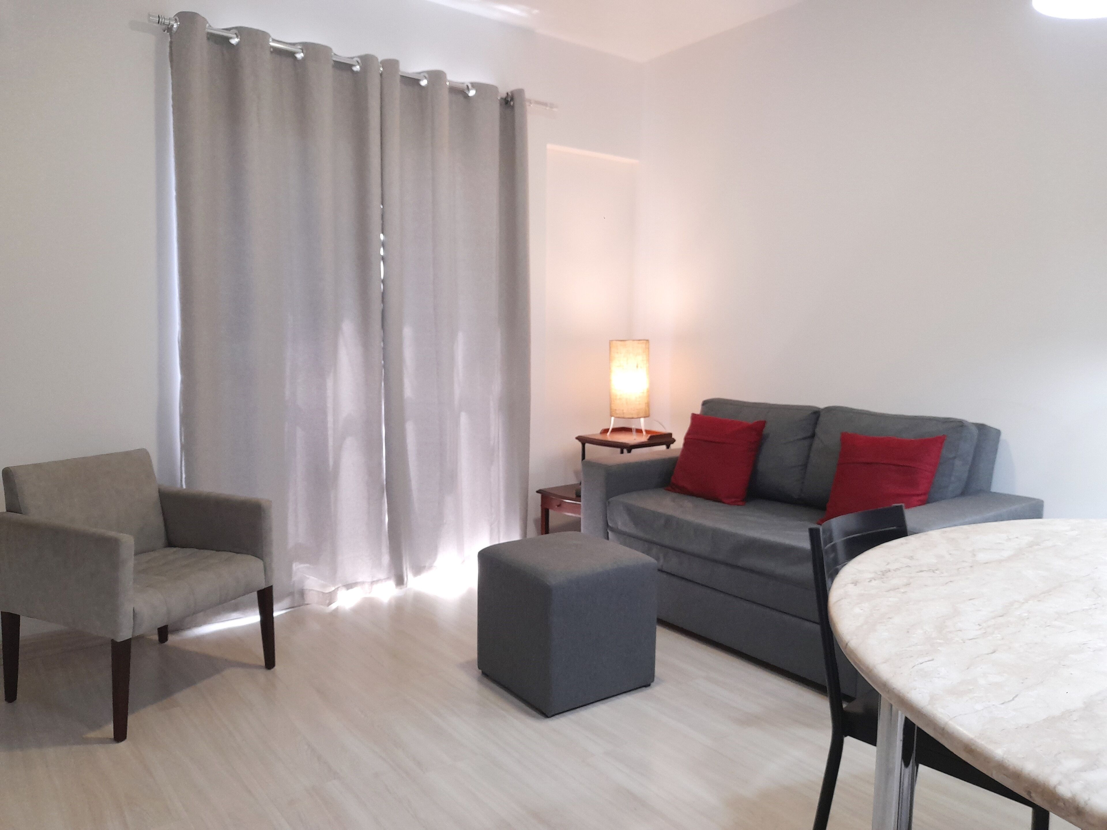 Una sala de estar con un sofá gris, un sillón gris, una mesita y una lámpara.