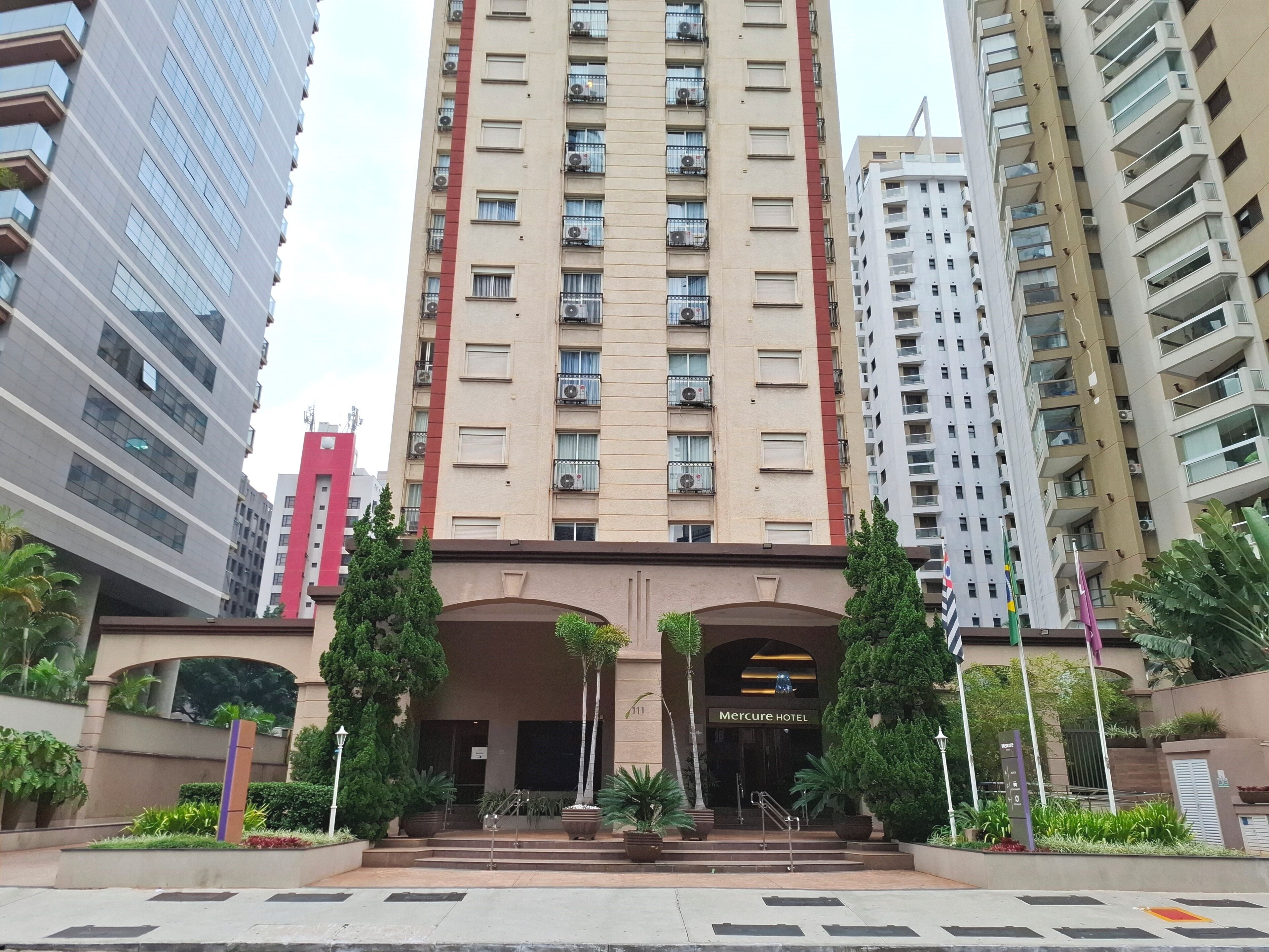 A high-rise building with a prominent entrance, multiple balconies, and a sign indicating it is a hotel.