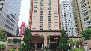 A high-rise building with a prominent entrance, multiple balconies, and a sign indicating it is a hotel.