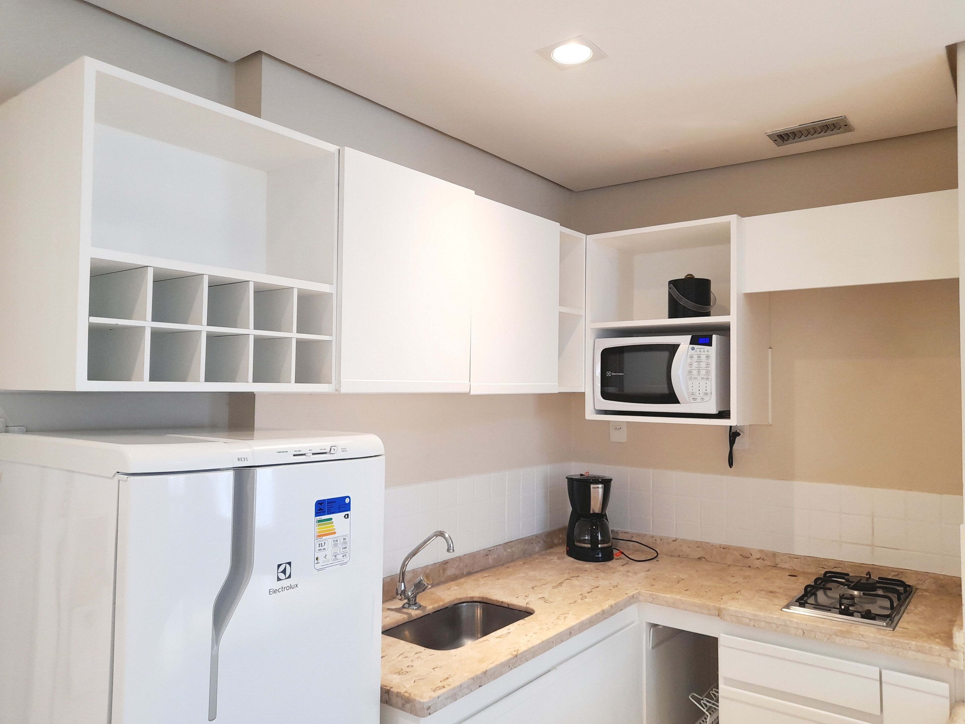 A kitchen with white cabinets, a microwave, a coffee maker, and a gas stove.