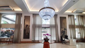 Un vestíbulo espacioso con una gran araña, una recepción y un diseño de interiores moderno.