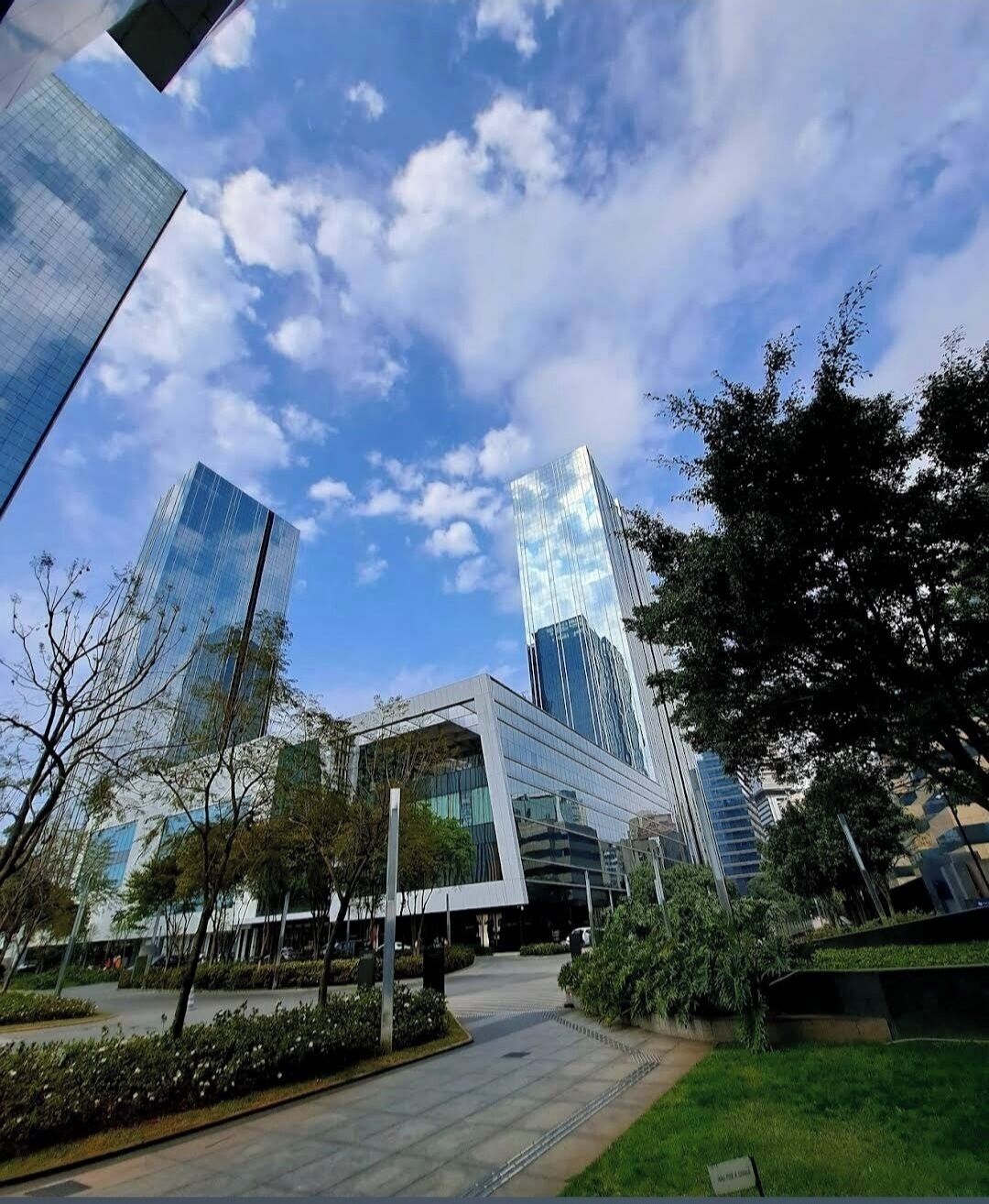 Un ensemble immobilier moderne, doté de façades en verre et d’une cour aménagée.