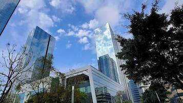 Un ensemble immobilier moderne, doté de façades en verre et d’une cour aménagée.