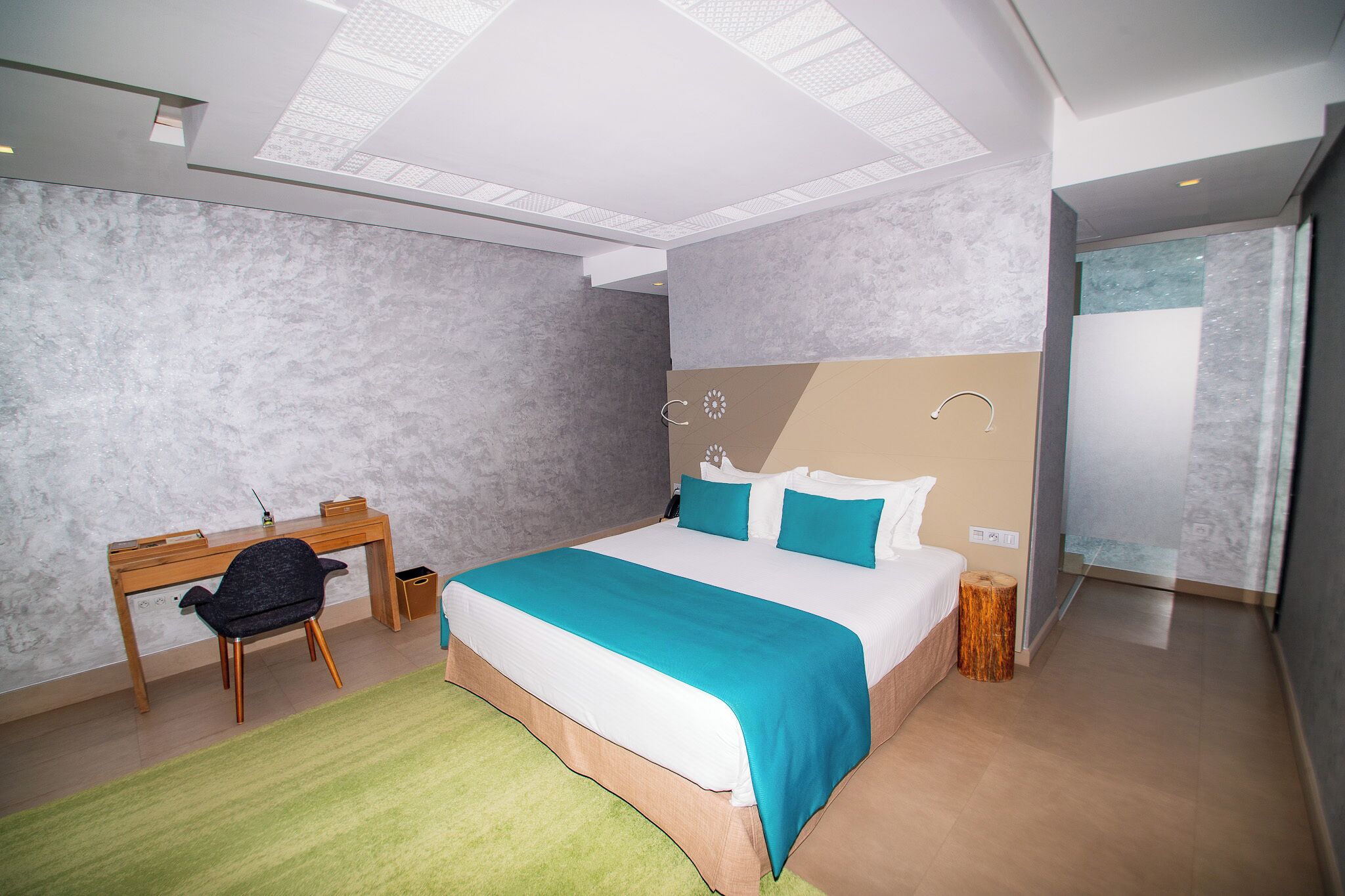 Ein modernes Hotelzimmer mit einem großen Bett, einem Schreibtisch und einem Sessel.