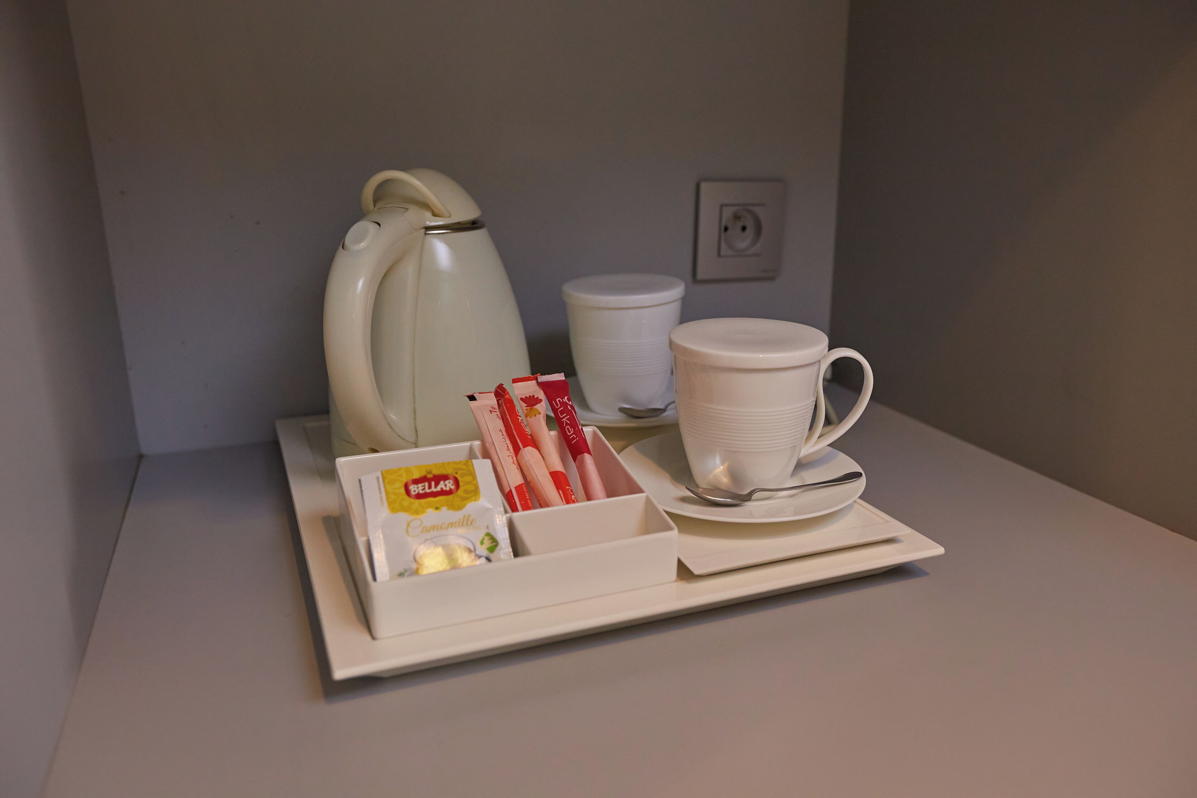 A tray with a white coffee pot, a white cup, a white saucer, and a box containing a pack of Belar coffee, a pack of cigarettes, and a pack of cigarettes.
