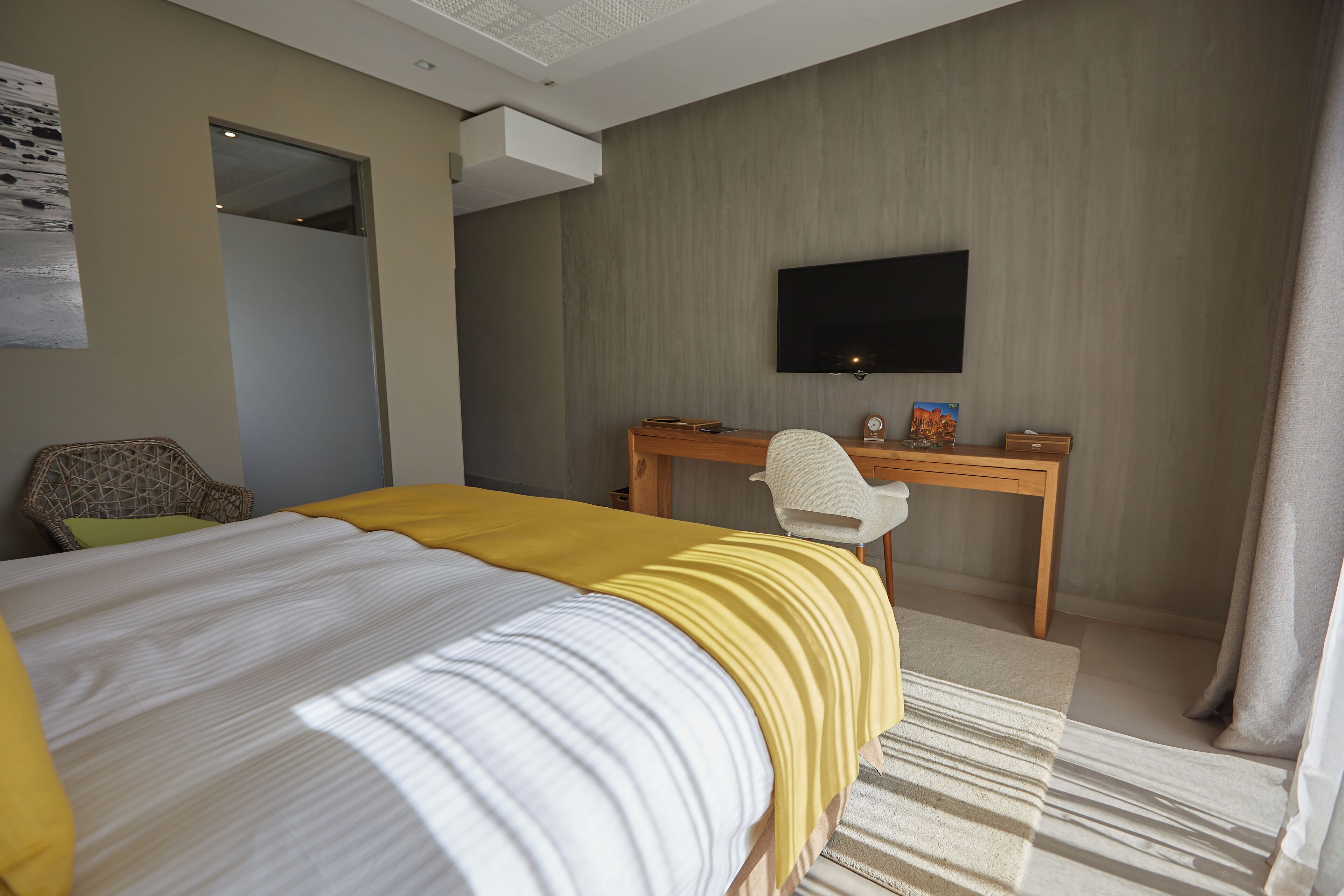Une chambre d’hôtel équipée d’un lit, d’un bureau, d’une chaise, d’un téléviseur à écran plat et d’une fenêtre avec des rideaux.