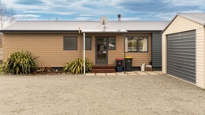 A single-story building with a beige exterior, a front door, and a satellite dish. - Restful on Rhoboro - Free Wifi (Twizel)