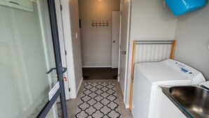 A compact bathroom with a white sink, a small window, and a blue bucket on the wall. - Restful on Rhoboro - Free Wifi (Twizel)