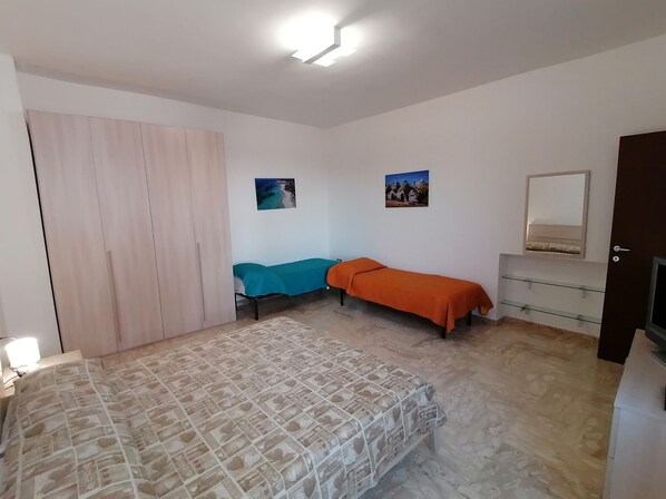 A bedroom with a bed, a wardrobe, a bedside table, a mirror, and two wall-mounted pictures.
