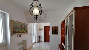 Un pasillo con candelabro, cuadros y un aparador de madera.