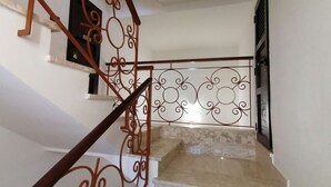 Una escalera con barandilla de madera y balaustradas metálicas decorativas.