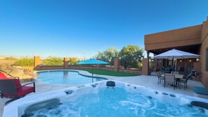 Een jacuzzi en een zwembad met ligbedden en parasols.