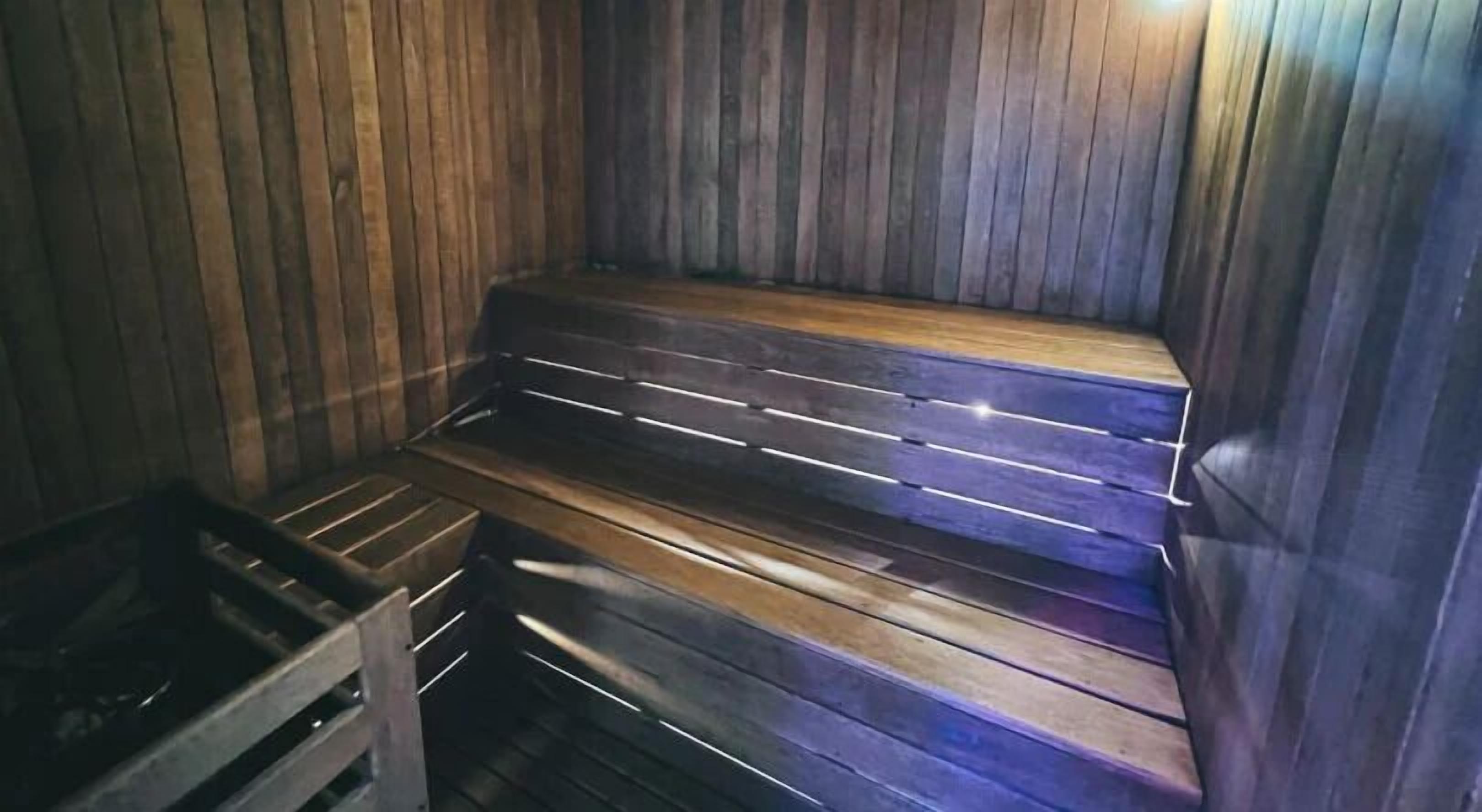 A sauna with wooden benches and a metal bench.