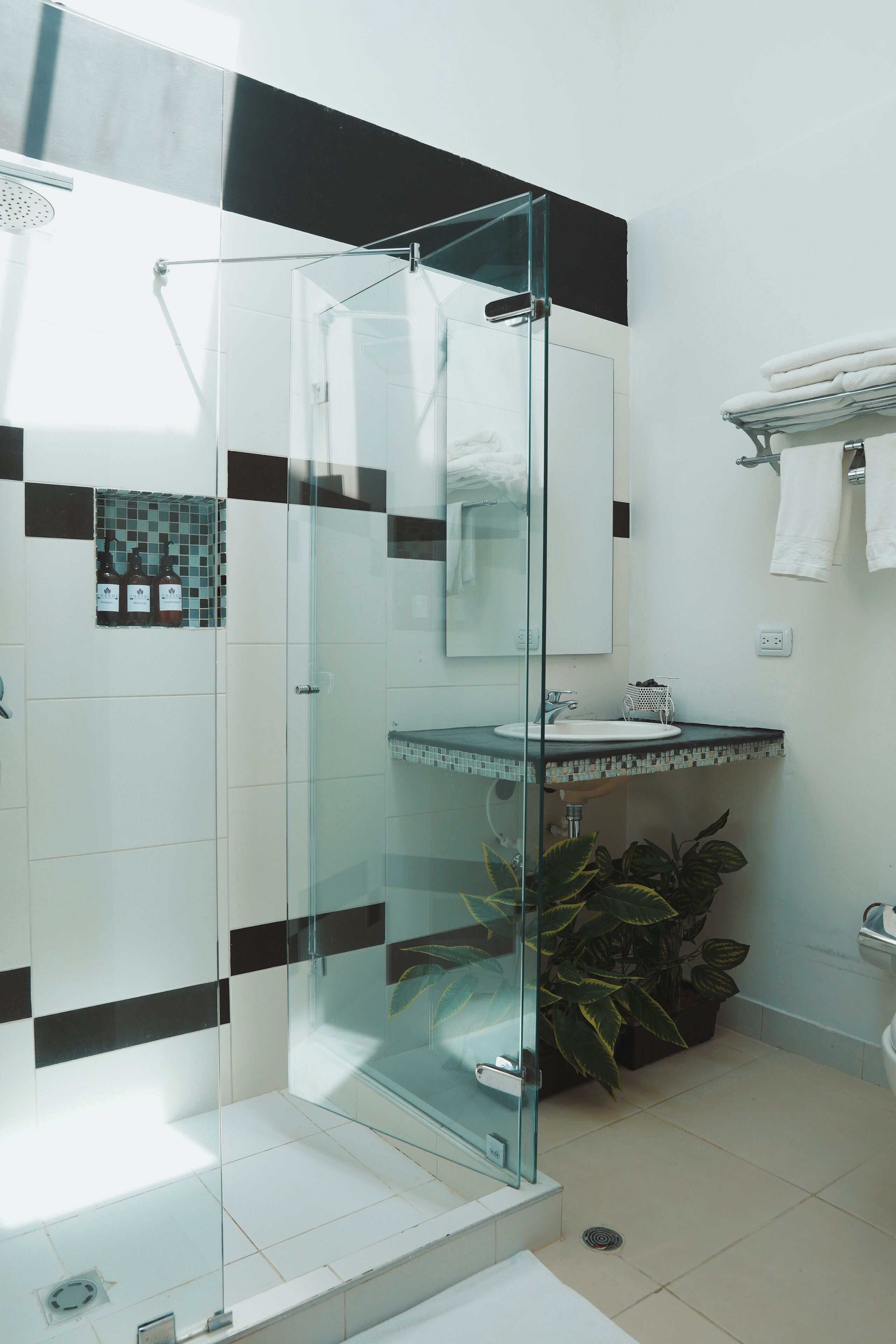 Un baño moderno con cabina de ducha de vidrio, un lavabo blanco y salpicadero de azulejos.