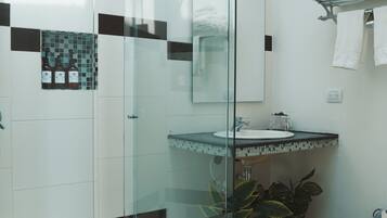 Un baño moderno con cabina de ducha de vidrio, un lavabo blanco y salpicadero de azulejos.