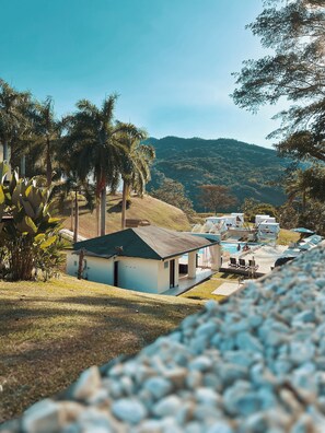 A small, single-story building with a pool area, surrounded by palm trees and a hilly landscape. - Dharma Hotel Boutique Spa (San Jerónimo)