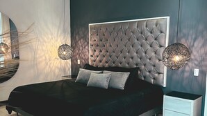 Een moderne slaapkamer met een gestoffeerd hoofdeinde, een groot bed, twee nachtkastjes en een spiegel van de vloer tot aan het plafond.