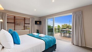 Une chambre à coucher avec un lit, une télévision et un balcon équipé d’une table et de chaises.