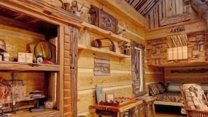 Interior rústico de una cabaña con paredes y techo de madera, y un comedor con mesa y sillas.