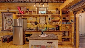 Una cocina rústica con paredes de madera, un refrigerador de acero inoxidable y diferentes utensilios y adornos de cocina.