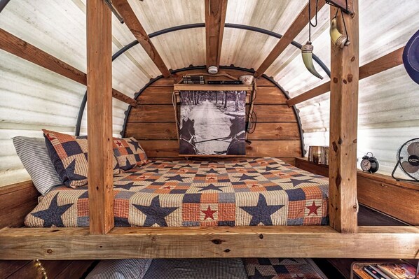 Un dormitorio acogedor y rústico con una cama litera de madera, colcha acolchada y un cuadro en la pared.