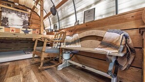 Eine rustikale Holzbank mit einer Decke, ein Holzstuhl und ein Tisch mit einer Vintage-Lampe.