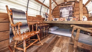 Ein gemütliches Interieur mit einem Schaukelstuhl aus Holz, einem kleinen Bett und einer Bank.