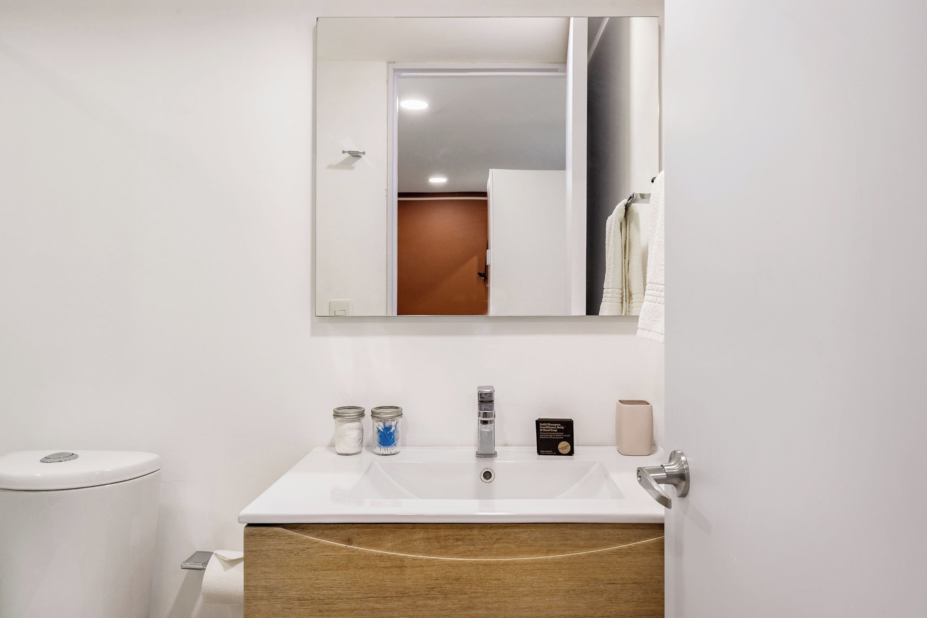 Une salle de bain avec un lavabo blanc, un miroir et des toilettes.