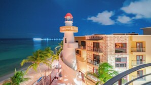 Un hôtel situé sur la côte, doté d’un phare, donnant sur la plage et possédant plusieurs balcons.