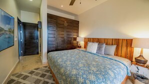 Une chambre à coucher avec un grand lit, une tête de lit en bois, une table de chevet, une lampe et une armoire.