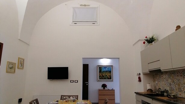 Ein Essbereich mit einem Tisch für vier Personen, einem an der Wand montierten Fernseher und einer Küche mit Schränken und einer Arbeitsfläche.