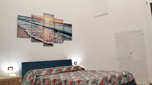 Ein Schlafzimmer mit Bett, Nachttisch, Wandbild und Kleiderschrank.