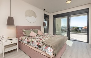 A bedroom with a bed, bedside table, lamp, and a large window with a view of the sea. - Awesome home in Banjol (Banjol)