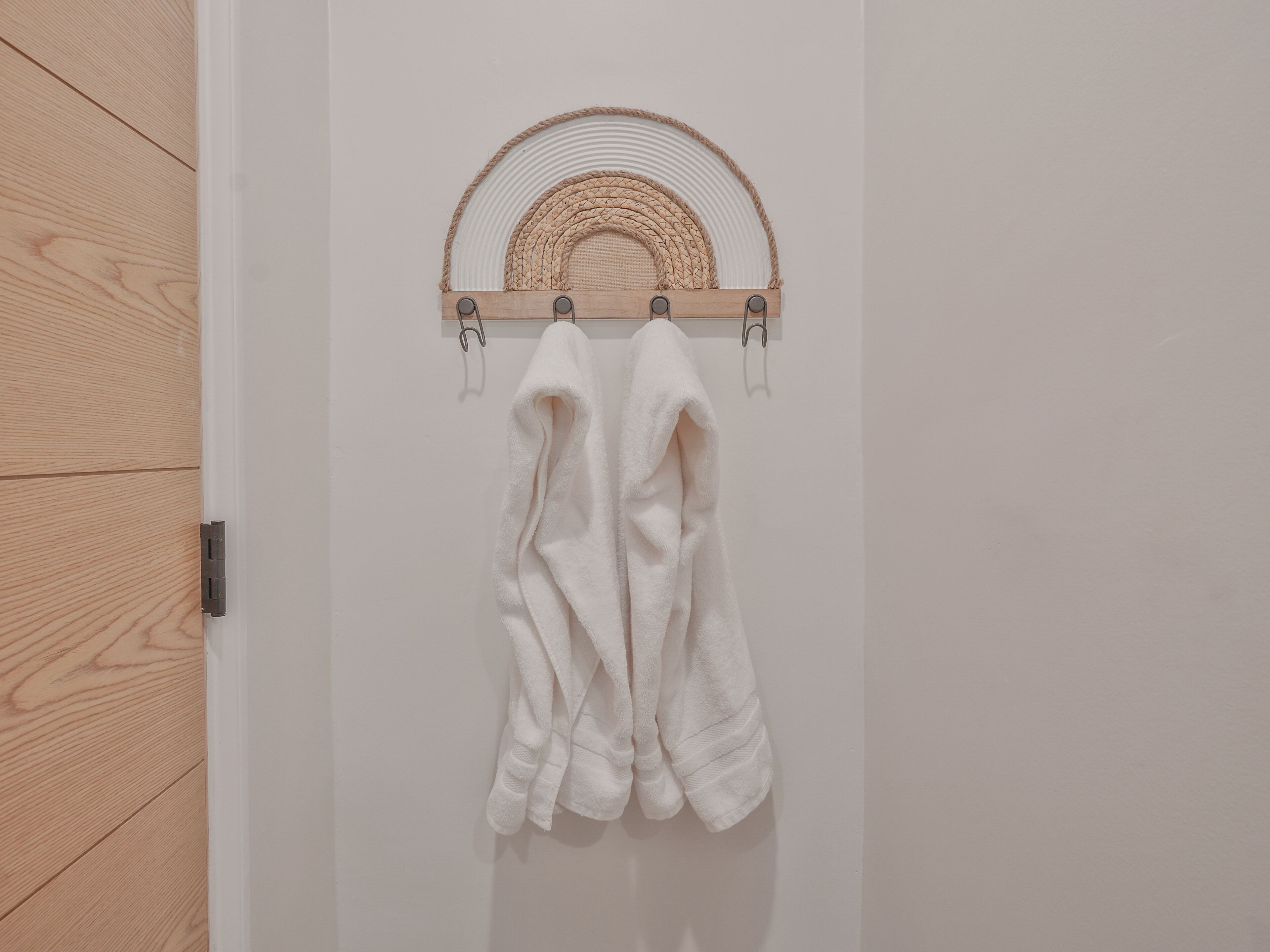 A white towel rack with two towels hanging on it, mounted on a white wall.