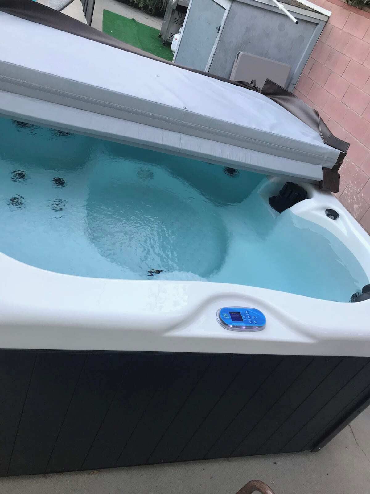 Un jacuzzi con panel de control, rodeado por una zona de patio.