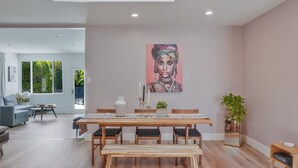 Un espace repas moderne avec une table en bois, des bancs et un tableau accroché au mur.