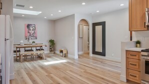 Une cuisine spacieuse avec des meubles en bois, un coin repas avec une table et des bancs en bois, et un grand miroir au mur.