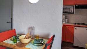 A dining table with a bowl, plates, and cutlery. A bright light fixture is mounted on the wall above the table.