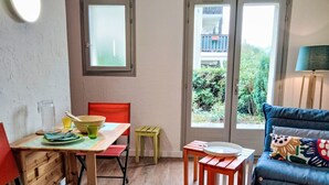 A cozy room with a wooden dining table, a red chair, a blue sofa, and a small wooden stool.