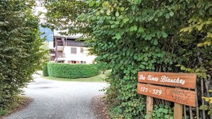 A wooden sign indicating 'Les Cimes Blanches' with a parking sign below.