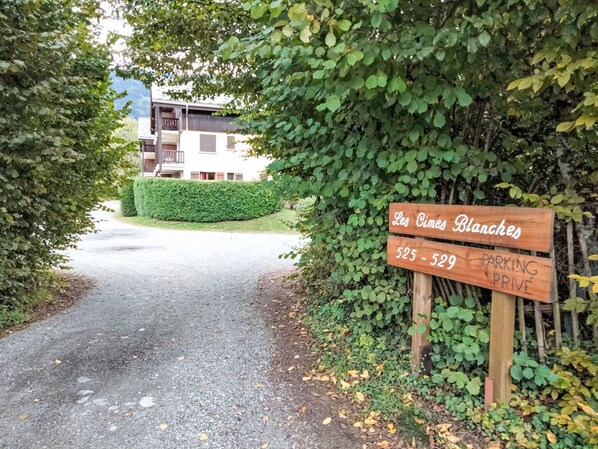A wooden sign indicating 'Les Cimes Blanches' with a parking sign below.